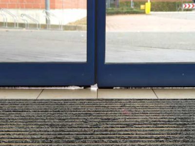 Sliding door of a retail store with leaky door brushes.